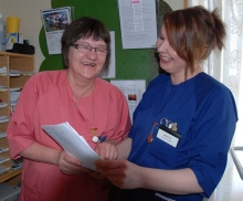Two health admin staff looking at a paper and smiling